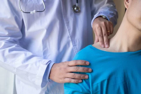 A physician palpating a patients shoulder.